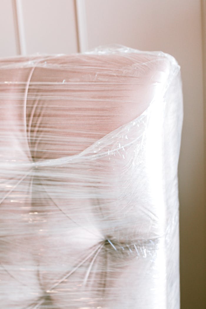 Close-up of a couch wrapped in plastic for protection during moving.